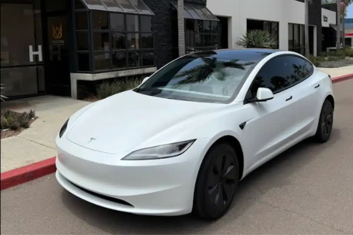 A white Tesla sedan parked outside a building, with a clean and modern design.