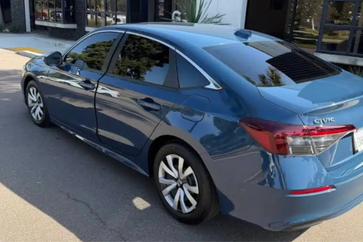 A blue Honda Civic sedan with tinted windows, parked outside a building.