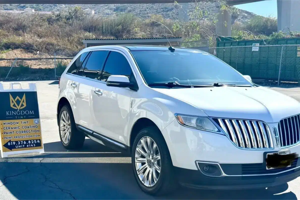 White SUV with paint protection film parked beside detailing shop sign