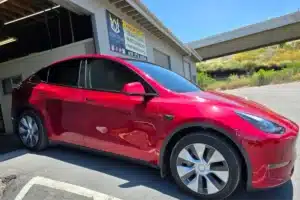 Red car with paint protection film outside a detail shop.