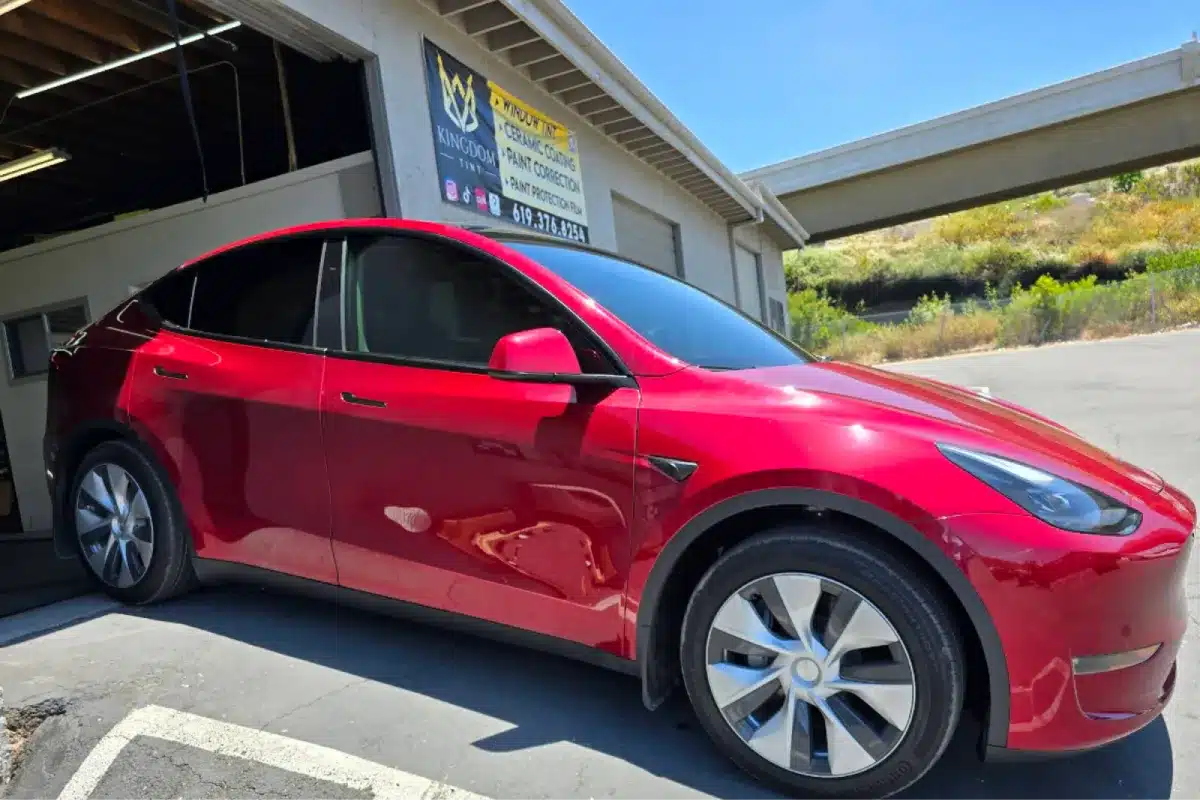 Red car with paint protection film outside a detail shop.