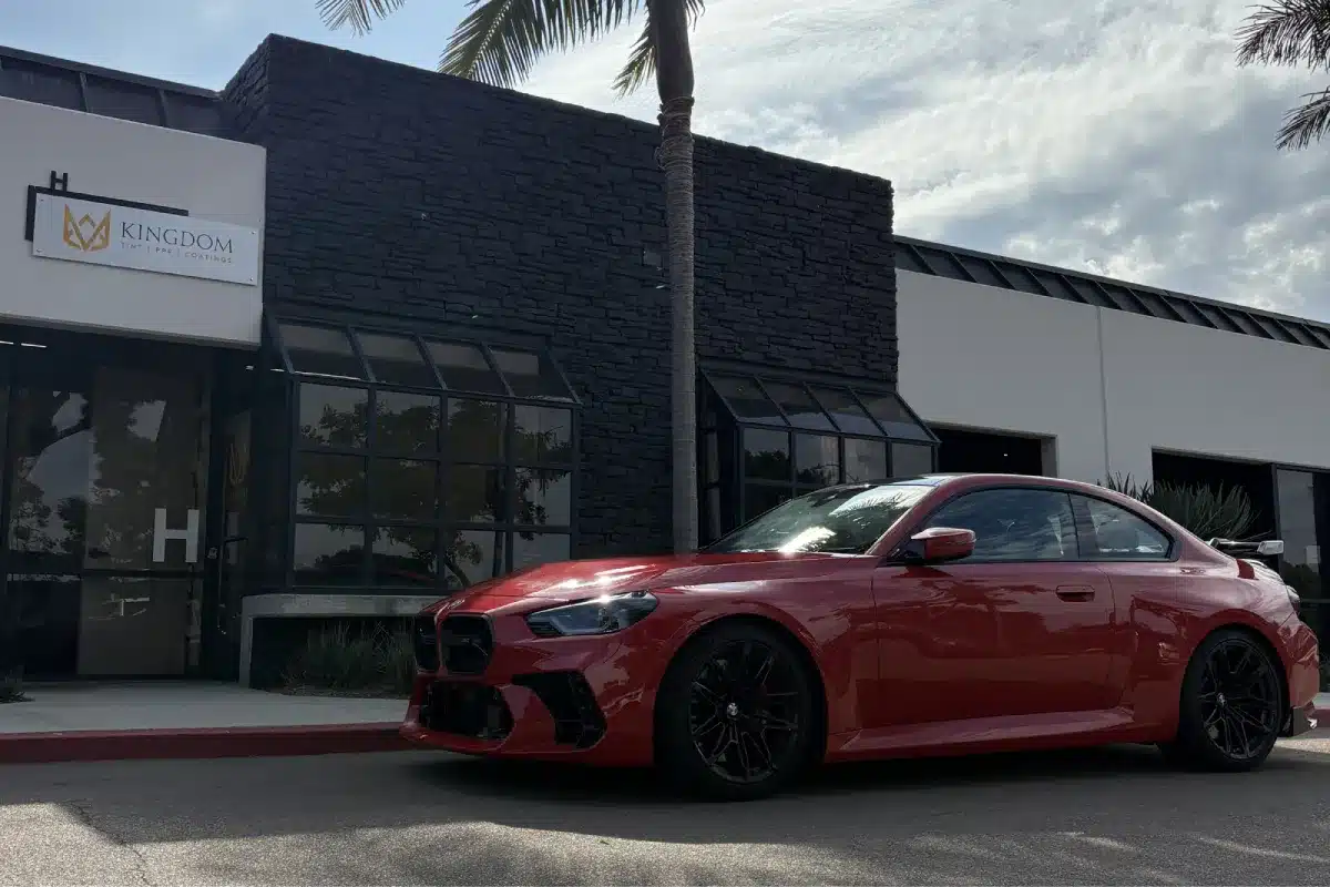 Red BMW coupe protected with paint protection film outside the shop.