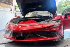Red Ferrari receiving paint protection film on the front end.